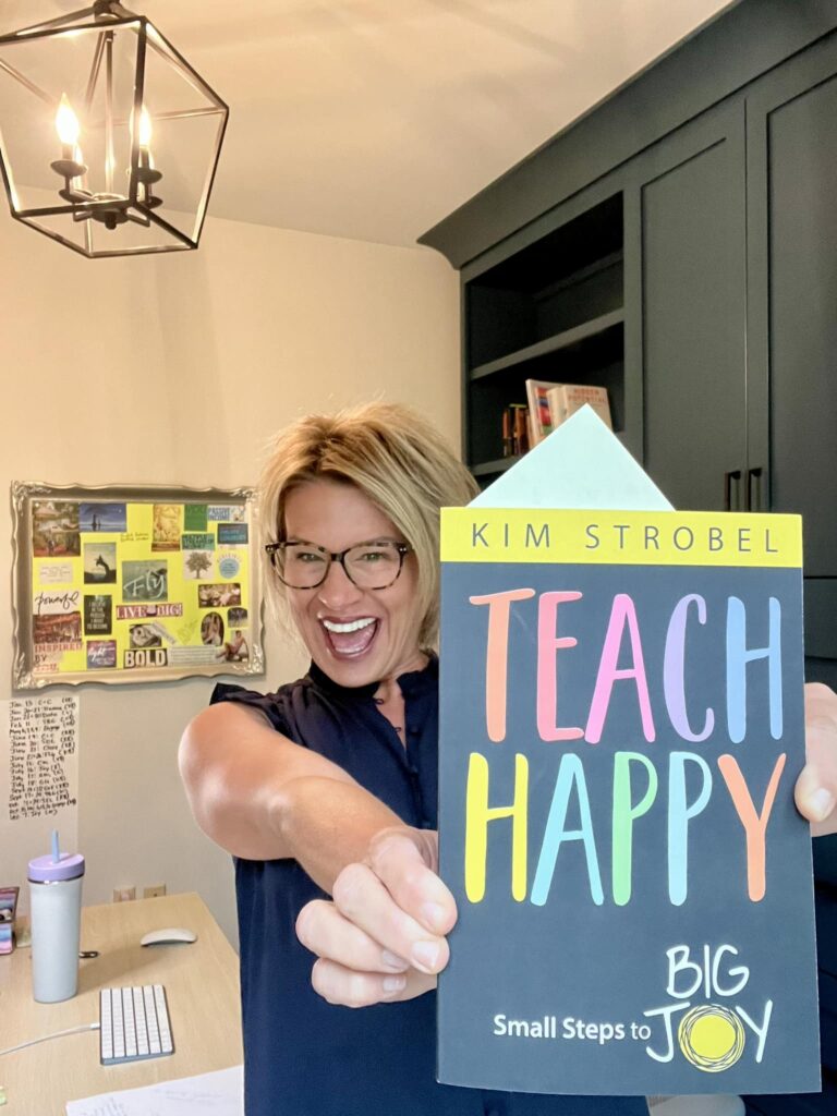 Kim Strobel holding the "Teach Happy" book.