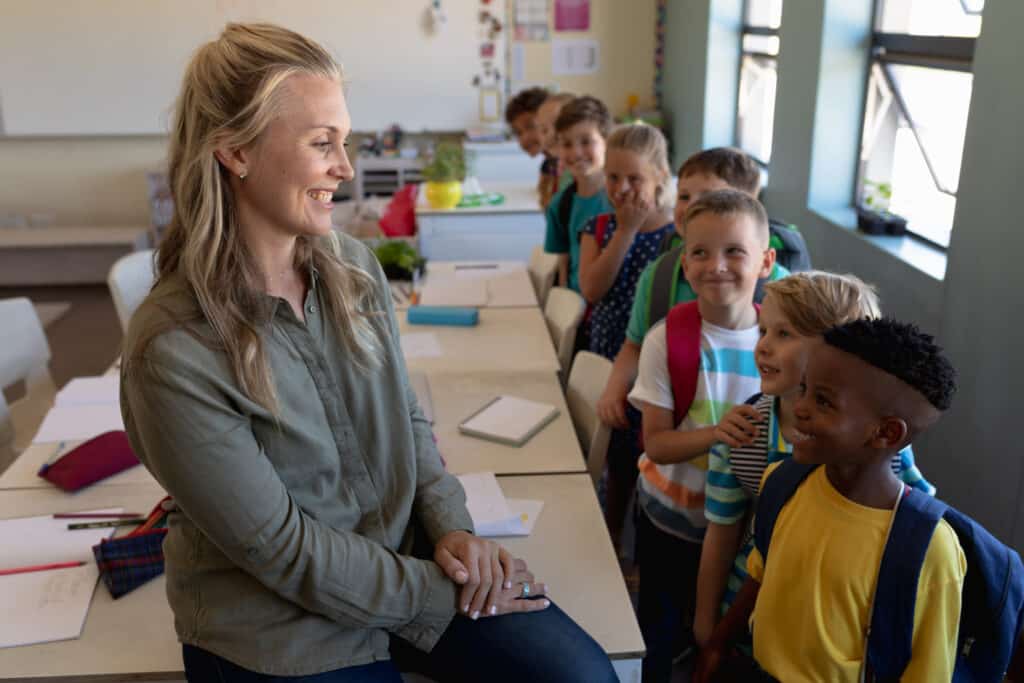 Side view of a happy female school teacher smiling at students in single file