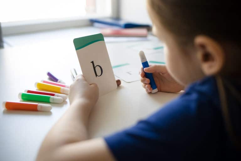 girl holds in her hands card with English letter orthographic mapping concept