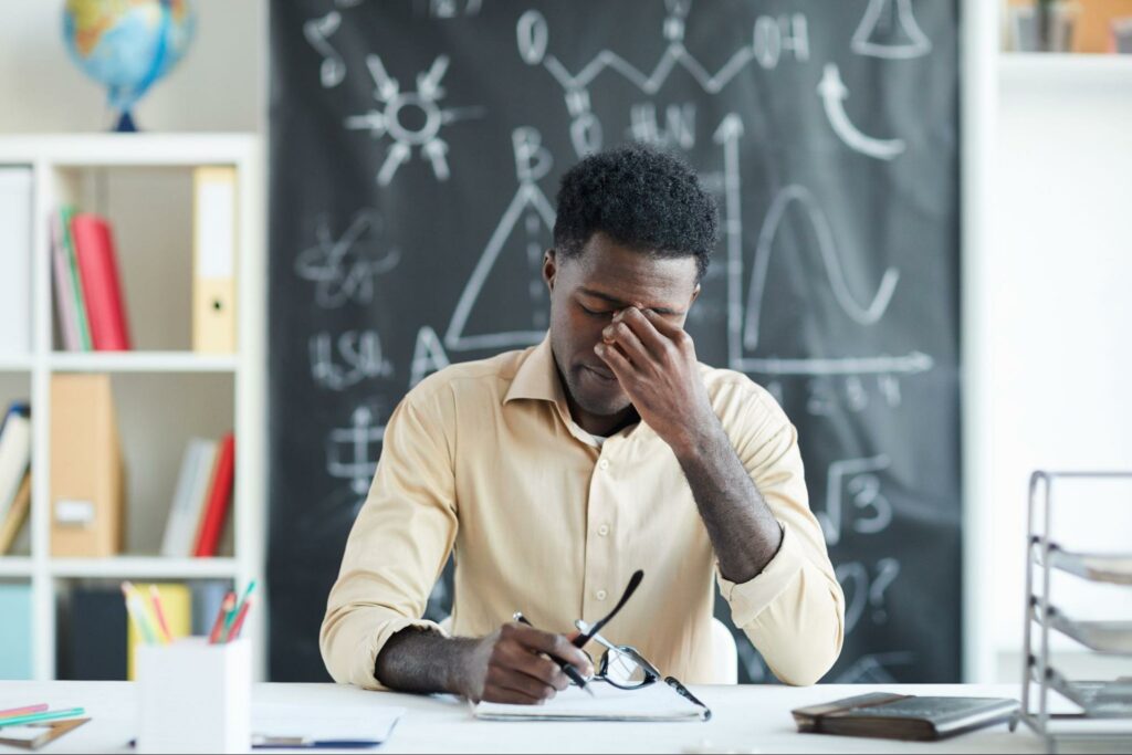 Overwhelmed teacher struggling with classroom challenges, feeling stressed and fatigued.