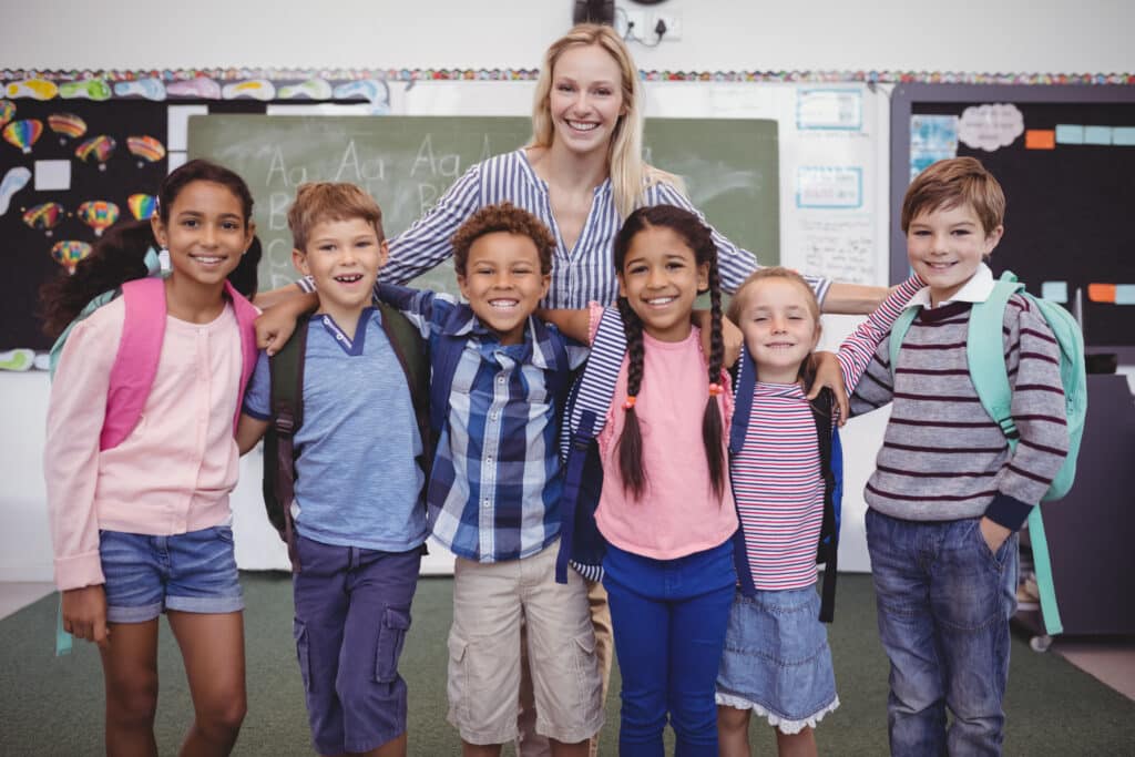 PERMA Model concept - happy-teacher-standing-with-schoolkids-in-classroom