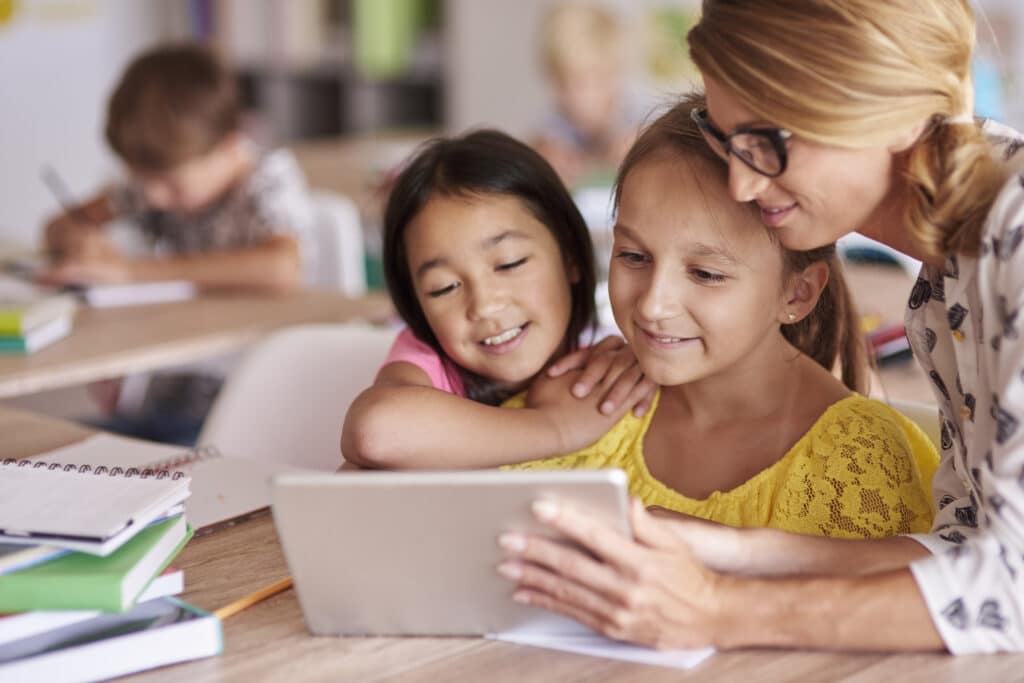 Student-centered learning concept -Teacher helping pupils with digital tablet