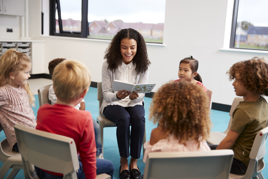 Female school teacher reading a book to kindergarten class
