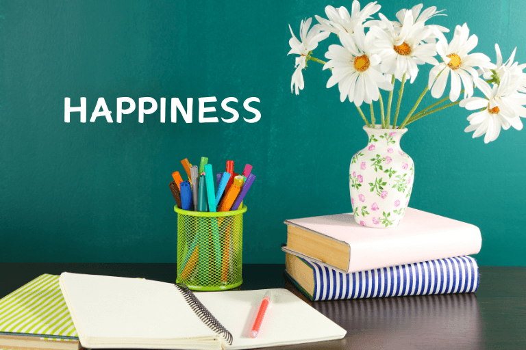 Various things on the table and board with the word "happiness" written on it