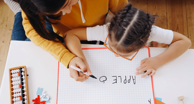 a woman who is a teachr teaching kid to write