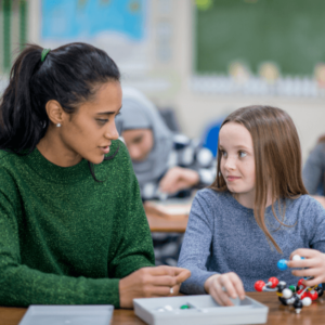 teacher sitting with student in the classroom