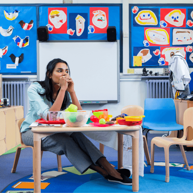 teacher in deep though looking stressed inside the classroom