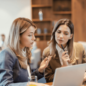 2 women talking in front of computer